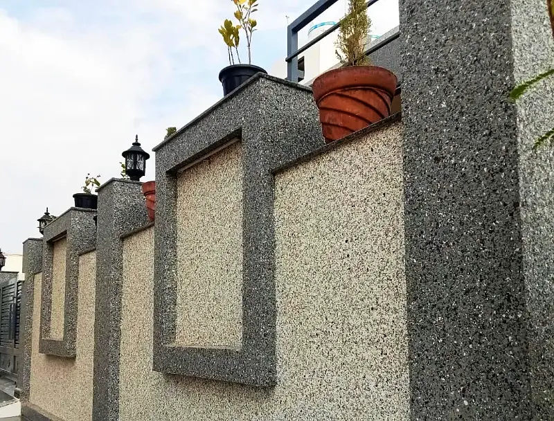 Boundary wall with light marble texture panels framed in dark grey